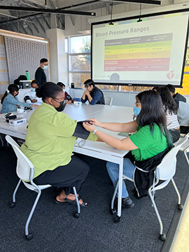 UI Health CHAMPIONS 2022 Summer Internship participants learning how to use and read an automatic blood pressure monitor.