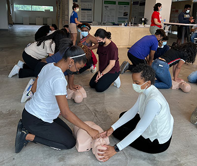 UI Health CHAMPIONS 2022 Summer Internship cohort participating in a bystander CPR training facilitated by Illinois Heart Rescue.