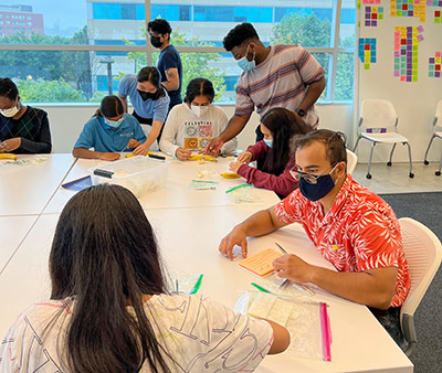 UI Health CHAMPIONS 2022 Summer Internship participants practicing suturing techniques guided by UIC College of Medicine student Ephraim Mbachu and CHAMPIONS coordinators.