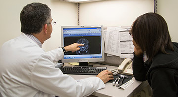 A male physician looking at a computer monitor with a female patient.