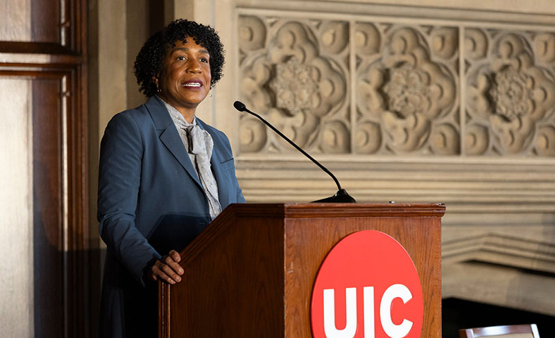 A women standing at a podium, talking.