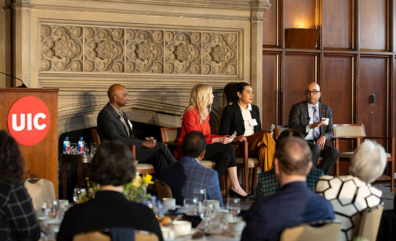 Four people sitting in front of a group, talking.