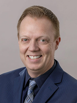 A man with in a suit, smiling at the camera