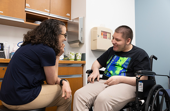 A female sitting and smiliing with a male in a wheelchair