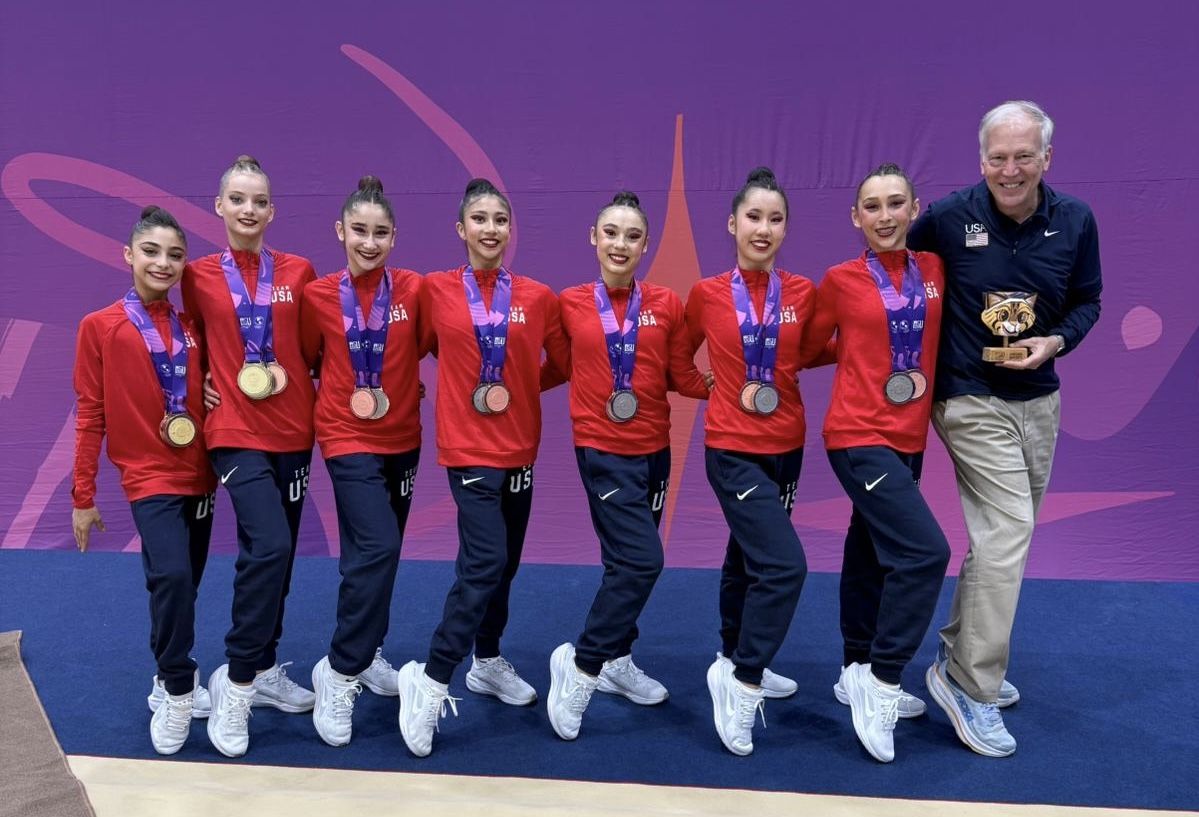 A man standing next to a line of female gymnasts
